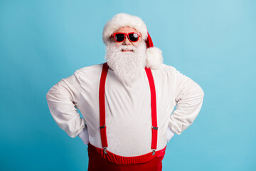 Fototapeta na wymiar Portrait of his he nice attractive cheerful cheery glad content thick white-haired Santa hands on hips holly jolly mood isolated over bright vivid shine vibrant blue color background