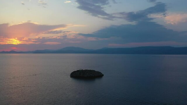 A small island in front of Vlychos Plakes Beach in Hydra Island, Greece. Sunset over Spetses