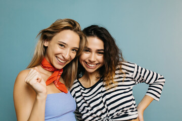 Two pretty positive girls smiling at camera. Young women having great time together. Blonde in blue...