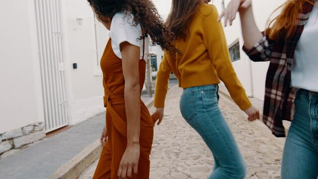 Group of girls dancing and enjoying outdoors on the street. Female friends dancing carefree outdoors.
