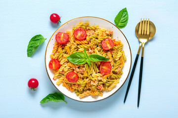Fusilli - classic italian pasta from durum wheat with chicken meat, tomatoes cherry, basil in tomato sauce in white bowl on blue wooden table Mediterranean cuisine Top view Flat lay