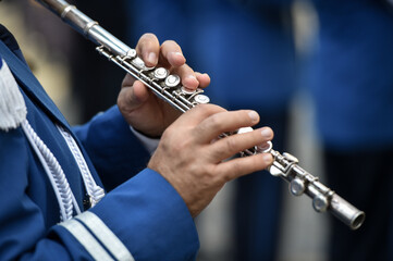 Military orchestra man performing during ceremony. Detail with musician hands playing on flute.