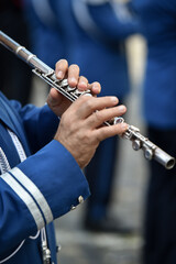 Military orchestra man performing during ceremony. Detail with musician hands playing on flute.