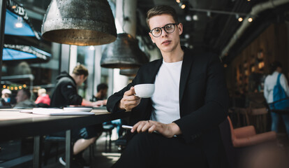 Confident student with cup of coffee in cafe