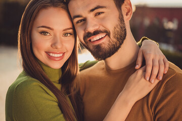 Fototapeta premium Portrait of positive affectionate couple girl guy embrace romantic in autumn park outdoors wear turtleneck sweater