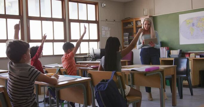 Group of kids raising their hands in the class at school