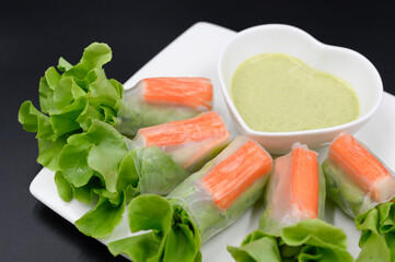 Vegetable salad with crab sticks with sauce on a white plate