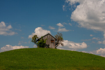 Scheune auf einem Hügel mit Wolken