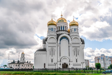 White Church with Golden domes with Eastern Orthodox crosses against a blue sky with clouds