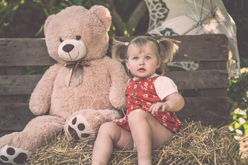 Süßes Kleinkind Mädchen mit rotem Kleid und Zöpfen großer Teddybär Sonnenschirm lächelt outdoor hölzener Hintergrund vintage Var. 11