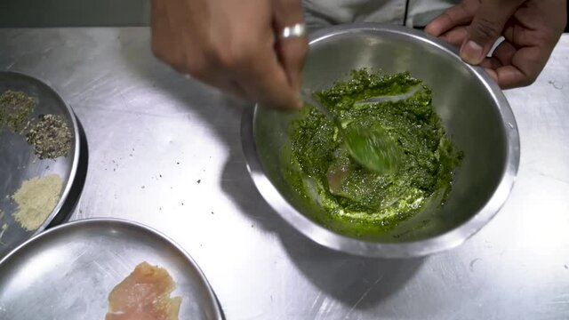 Chermoula Sauce In A Silver Bowl Spread On Chicken Meat Using Spoon. - Close Up-topdown Shot