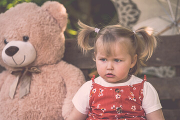 Süßes Kleinkind Mädchen mit rotem Kleid und Zöpfen großer Teddybär Sonnenschirm böse schauend outdoor hölzener Hintergrund vintage Var. 9