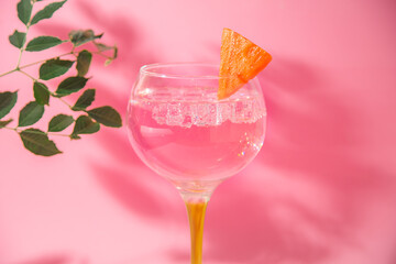 gin and tonic glass on pink background