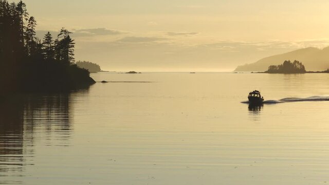 Small Fishing Boat with Kayak Silhouetted Against Sunset and Reflective Waters of Southeast Alaska Inside Passage