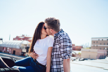 Caucasian couple in love 20s kissing during date cuddling and flirting, casual dressed hipster guys in mockup t-shirt enjoying tenderness relationship during together pastime at house roof