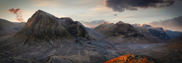 panoramic view of sunrise with tourist on mound in Glencoe, Highlands, Scotland.