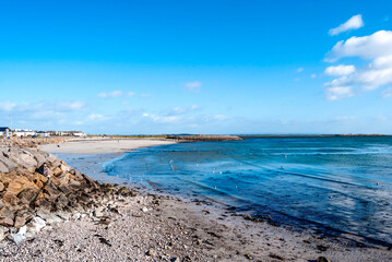 The coast in Salthill overlooking Galway Bay, Ireland, along the Promenade in a sunny bright day, with sand, rocks and blue cristalline water.