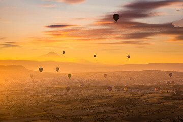 Hot air balloons flying over a volcanic landscape at Cappadocia, Turkey.