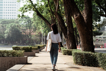 Back view - University student walking at park.