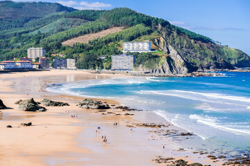 View of the beach of Bakio town. People walk on the sand at low tide. Near Bilbao and Gaztelugatxe, Basque Country, Northern Spain