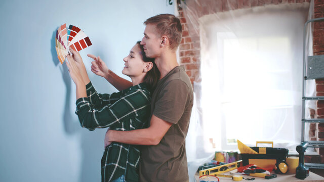 Young Couple Choosing Paint Color From Samples For New Home Interior Design