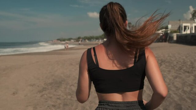 Sportswoman running along sandy coastline