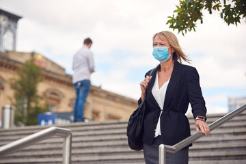 Mature Businesswoman Wearing PPE Face Mask Walking Outdoors In Street During Health Pandemic