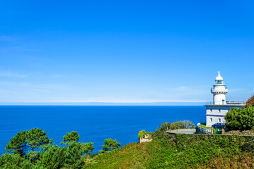 Fototapeta na wymiar white lighthouse on the shore against the blue sea. Donostia San Sebastian, Basque Country, Spain. Copy space