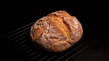 Hogaza de pan rústica hecha con harina de trigo en un fondo negro.
