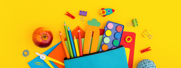 Pencil case and school supplies on yellow background