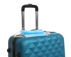 Stylish blue suitcase and protective masks on white background. Travelling during coronavirus pandemic