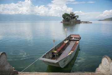 Boat docking in the lake, in the background a house on a small island. Area of Dali, Yunnan, China