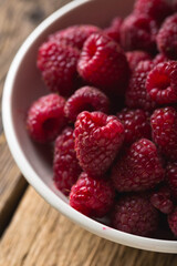 Fresh raspberries in a bowl on a wooden table