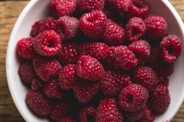 Fresh raspberries in a bowl on a wooden table