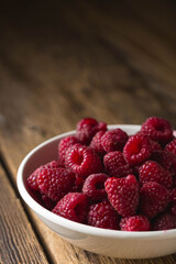 Fresh raspberries in a bowl on a wooden table