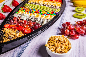 Acai frozen with banana, kiwi fruit, granola and candies for share. A boat for share.