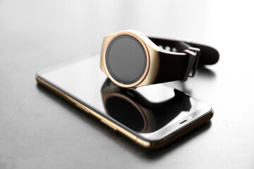 Stylish smart watch and phone on grey table, closeup