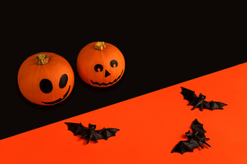 Little pumpkins with painted faces for Halloween and bats on orange and black background
