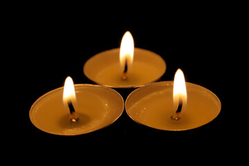 Three burning candles. Christmas candles burn in the dark. Focus is in the foreground