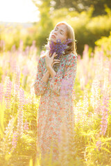 Portrait of beautiful blonde woman with bouquet of lupin flowers in her hands