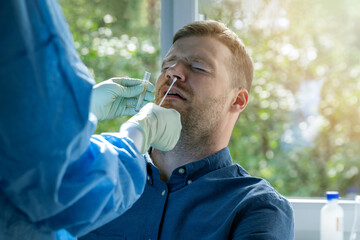 coronavirus nasal swab test -  lab worker taking a mucus sample from male patient nose