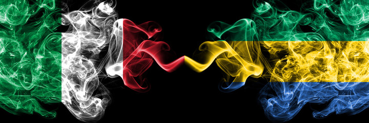 Italy vs Gabon, Gabonese smoky mystic flags placed side by side. Thick colored silky abstract smoke...