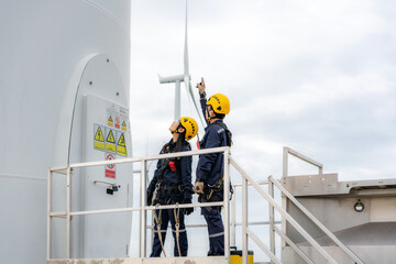 Asian man and woman Inspection engineers preparing and progress check of a wind turbine with safety...