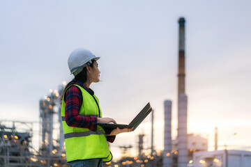 Asian woman petrochemical engineer working at night with notebook Inside oil and gas refinery plant...