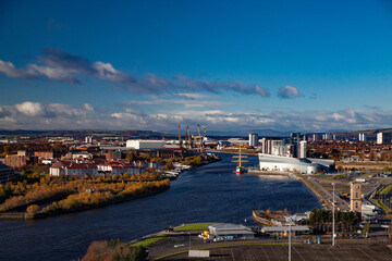 Fototapeta premium Glasgow, Scotland. Clyde river embankment. Riverside Museum and The Tall Ship at Riverside. Panorama view. Yellow trees. Blue sky, clouds.
