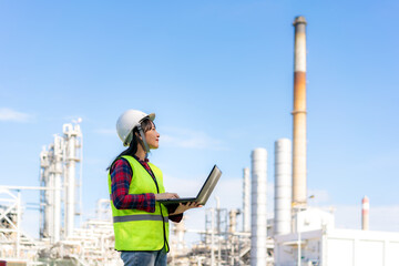 Asian woman petrochemical engineer working at night with laptop Inside oil and gas refinery plant...
