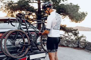 Obraz premium Male cyclist loading his bicycle on a rack of his crossover car