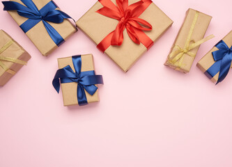 gift boxes wrapped in brown paper and tied with a red and blue bow, gifts on a pink background