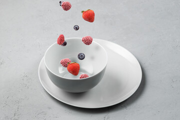 Frozen berries fall into a gray bowl.