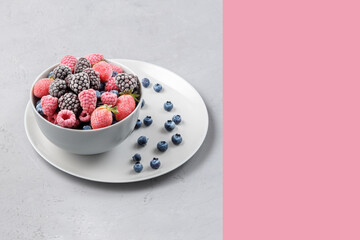Frozen berries in a grey bowl on a grey concrete background.